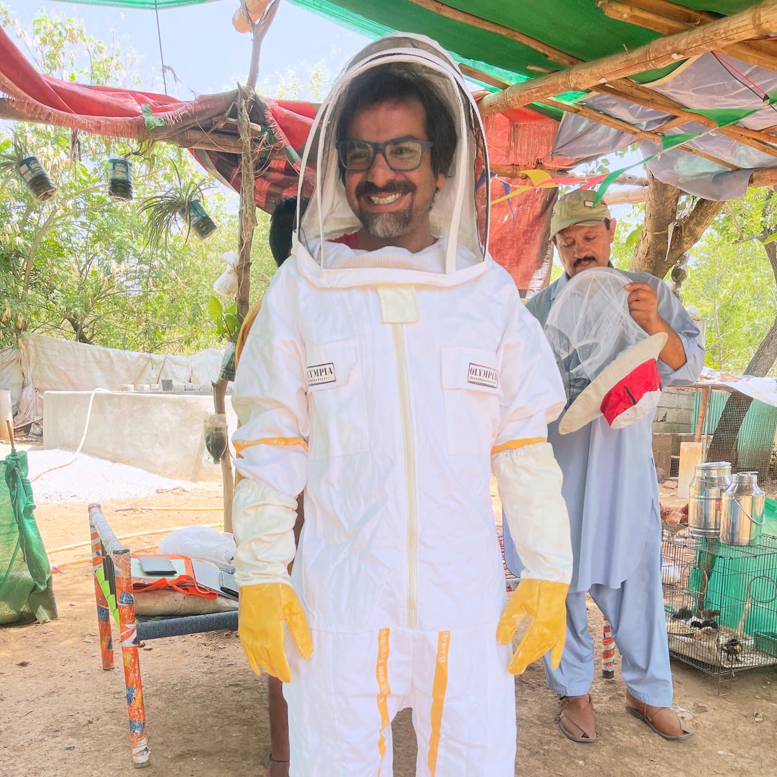 Umair smiling in a beekeeping suit at the From Zero farm in Chak Shahzad